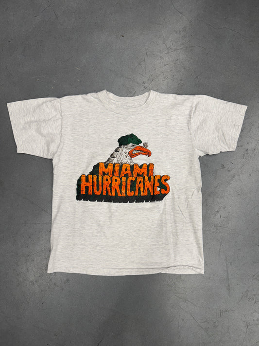 1990 MIAMI HURRICANES INSIGNIA SEBASTIAN WITH SPELL-OUT ROCK FONT TEE (PULLED TAG)